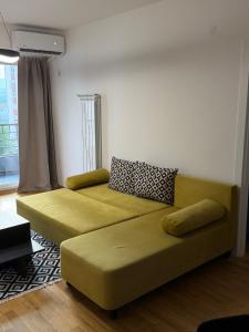 a living room with a yellow couch and a window at Skopje Riverfront Modern Apartment in Skopje