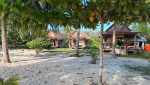 a group of houses with thatched roofs and trees at Mentawai Tribe Experience & Private Beach Camp in Pulau Masilo +65 photos
