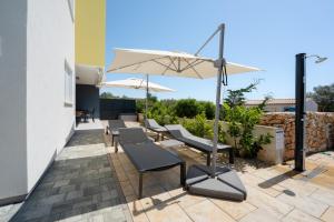 a row of chairs and an umbrella on a patio at Residence Giardino in Ugljan