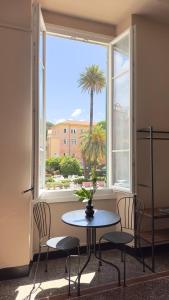 a table and chairs in front of a window with a palm tree at Hotel Fernanda in Rapallo