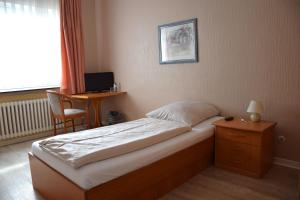 a bedroom with a bed and a desk and a window at Hotel Stadt Lübeck in Timmendorfer Strand
