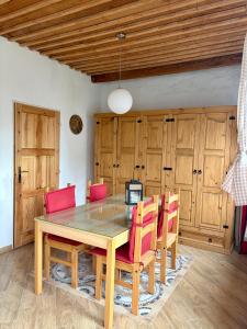 a dining room with a wooden table and red chairs at Domek u vína in Perná