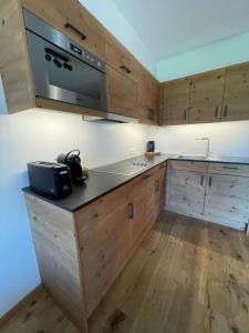 a kitchen with wooden cabinets and a microwave at Zugspitzblick - pur! in Lermoos