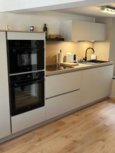 a kitchen with white cabinets and black appliances at Week end à Spa in Spa