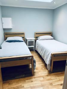 two twin beds in a room with wooden floors at Whiteleys Cottages 2 bedroom in Renton