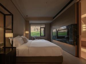 a bedroom with a large white bed and a window at Hayama Pagoda Villa in Taizhou