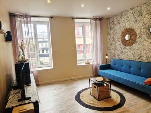 a living room with a blue couch and two windows at Le Key Largo in Cherbourg en Cotentin