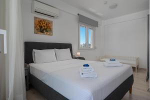 a bedroom with a white bed with towels on it at SLV Dionysos Apartment in Ofrínion