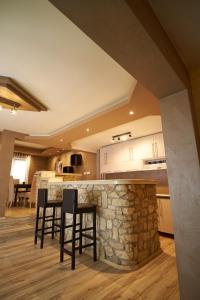 a kitchen with a stone bar with two stools at YAMM Pool House in Mali Požarevac