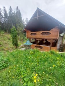 a wooden cabin with a black roof in a field of flowers at КОТЕДЖ У ЛІСКУ in Vorokhta +1 photo