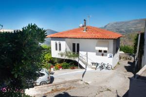 a white house with a car parked in front of it at EMPHASIS Traditional House with Jacuzzi & Bicycles in Apodhoúlou