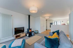 a living room with a blue couch and a fireplace at Residence Number 5 - Luxury 2 Bed Ground Floor Apartment By Together Travel in Nefyn