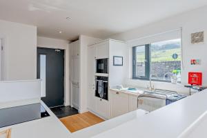 a white kitchen with a sink and a window at Residence Number 5 - Luxury 2 Bed Ground Floor Apartment By Together Travel in Nefyn