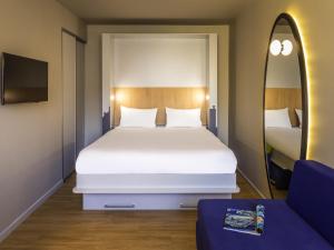 a bedroom with a large white bed and a mirror at Aparthotel Adagio access Montpellier Centre in Montpellier