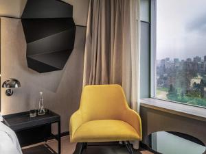 a yellow chair in a room with a window at Pullman Santiago Vitacura in Santiago