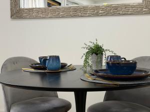 a black table with blue cups and plates on it at Sopianae Apartments in Pécs