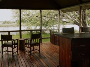 a screened in porch with a table and chairs and a bar at Muchenje River Lodge in Katima Mulilo