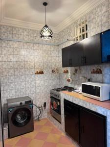 a kitchen with a washing machine and a microwave at IGBADUN House in Godomey
