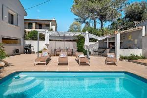 a swimming pool with lounge chairs and a house at Les Arbousiers in Saint-Raphaël