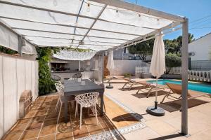 a patio with a table and chairs under a pergola at Les Arbousiers in Saint-Raphaël