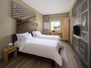 a hotel room with two beds and a television at Ibis Jeddah Malik Road in Jeddah