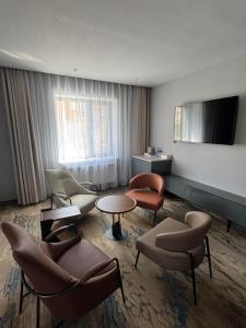 a living room with chairs and tables and a television at Happiness Hotel Ulaanbaatar in Ulaanbaatar