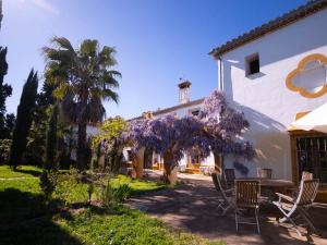 a house with a table and chairs and purple flowers at Cortijo Negretti in Herrera de Alcántara