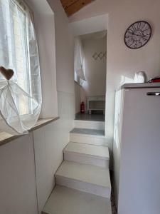 a small kitchen with stairs and a clock on the wall at Casa Ravasio in Arcevia +2 photos
