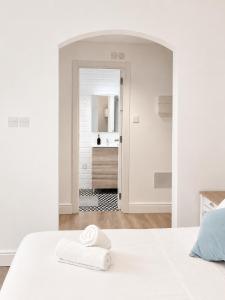a white bedroom with a white bed and a bathroom at Grand Central House - Deluxe Studio - GibraltarStay Apartments in Gibraltar