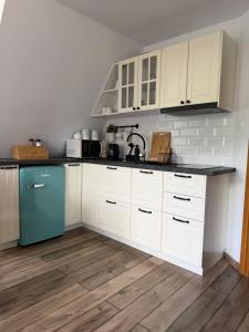 a kitchen with white cabinets and a blue refrigerator at Apartament u SKOCZKA in Poronin