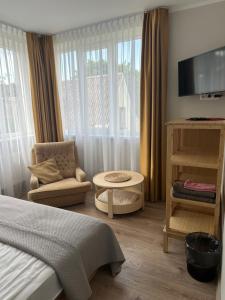 a bedroom with a bed and a chair and a tv at NB Apartamentai in Palanga +21 photos