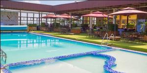a large swimming pool with blue water and tables and umbrellas at Ansan Comfort in Gatunga