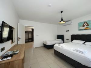 a bedroom with two beds and a flat screen tv at Parli Hotel in Gokceada Town