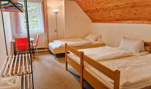 a bedroom with two beds and a red chair at Chalupa Šumburk in Svárov