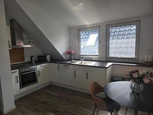 a kitchen with white cabinets and a table and two windows at Der Stader Fernblick in Stade