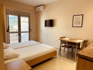 a room with two beds and a table and a television at Thoma's K Studios in Vlorë