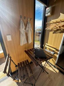 a table with a laptop on it next to a wall at The Dairy and Pines Tiny house by Tiny Away in Shadforth