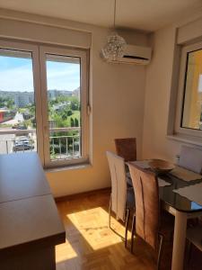 a dining room with a table and chairs and a window at Vels Suite - Cozy Oasis & Free Parking in Voždivac