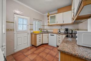 a kitchen with white cabinets and a tile floor at Casa Sol in Praia do Carvoeiro