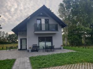a small white house with black tables and chairs at Dom Wakacyjny U Darka in Smołdzino