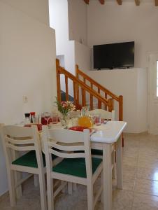 a white dining room table with chairs and a television at Villa Pefkias in Skopelos Town