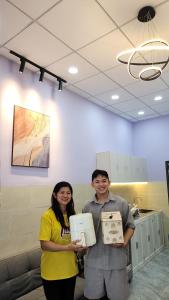 a man and a woman holding boxes in a room at Minihouse Út Thiểu in Rạch Giá