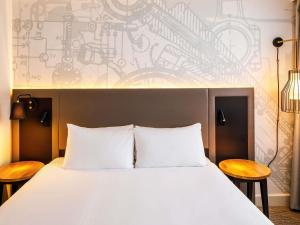 a bedroom with a large white bed with two chairs at Mercure Birmingham West Hotel in West Bromwich