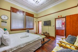 a bedroom with a bed and two chairs and a tv at The 196 City Lodge in Pretoria