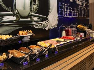 a buffet line with different types of bread and pastries at ibis budget Itaperuna in Itaperuna