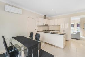 a kitchen with white cabinets and a glass table at Leopold holiday home in Leopold +5 photos