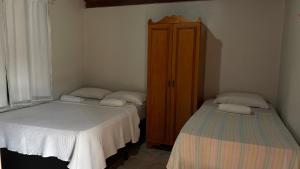 two twin beds in a room with a cabinet at Suítes Dona Ilda in Pirenópolis