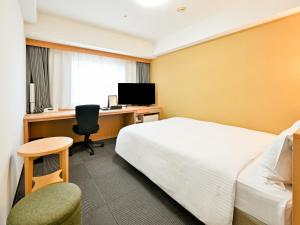 a hotel room with a bed and a desk with a computer at Richmond Hotel Hakata Ekimae in Fukuoka
