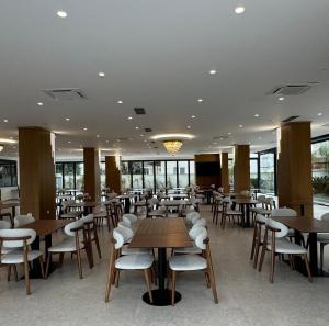 a restaurant with wooden tables and chairs and windows at Hotel Kraja in Golem