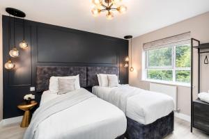 two beds in a bedroom with a black wall at Riverside Villas in Manchester